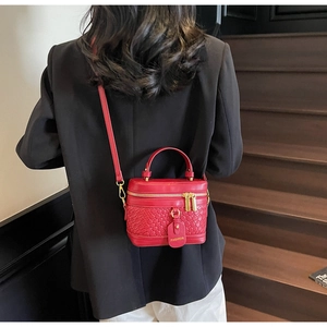 Detail of red PU leather bucket bag featuring woven texture and gold hardware zipper