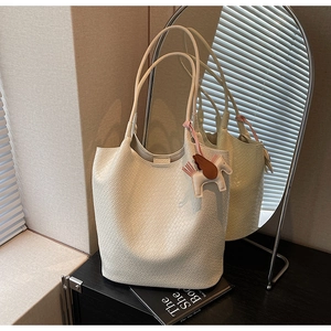 Detail view of white woven texture tote bag featuring a decorative pink horse charm