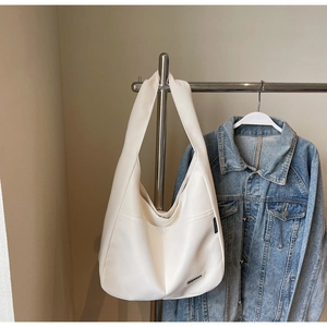 Detail view of cream tote bag with black woven label on high-quality matte leather