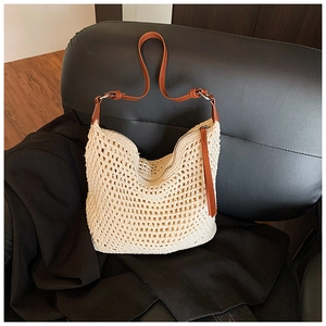 Close-up of woven hollow beach bag with leather strap and metal zipper detail