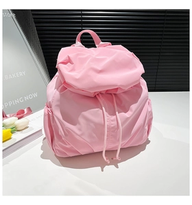 Detail of light pink nylon backpack featuring drawstring closure and waterproof fabric