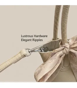 Close-up of white pebble leather handbag with silver buckle and elegant silk scarf