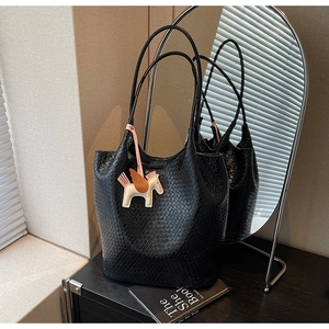 Detail of black woven leather tote bag with stylish winged horse charm on handles
