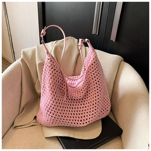 Detail of pink hand-woven hobo bag with leather strap and metal buckle on armchair