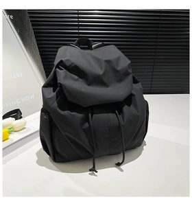 Detail of black pleated nylon backpack with drawstring closure and water-resistant fabric