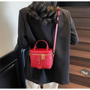 Detail shot of the red woven leather texture and gold hardware on the bucket bag