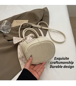 Detail of cream bucket bag featuring lychee texture and plaid ribbon scarf on handle