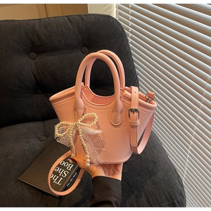 Detail of pink faux leather bucket bag with pearl bow decoration and lace trim accent