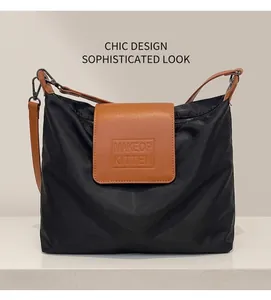 Détail d'un sac en nylon noir avec rabat en cuir marron et logo MAKEOP KITTEN embossé
