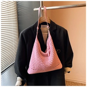 Detailed close-up of pink crochet woven shoulder bag with leather strap for beach vacation