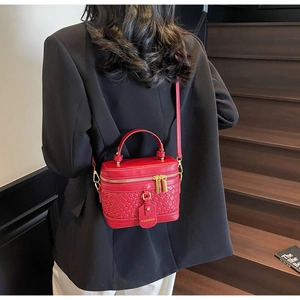 Detail of red woven texture bucket bag with gold hardware worn by a model in black suit