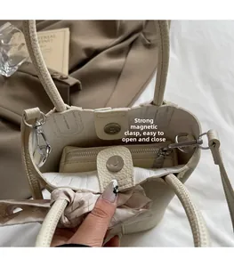 Detail view of cream bucket bag with magnetic closure, silk scarf, and inner pouch