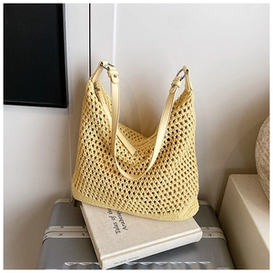 Detail of hand-woven hollow straw hobo bag with leather strap on a decorative book