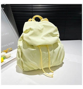 Detail of light yellow nylon backpack with drawstring closure and pleated side design