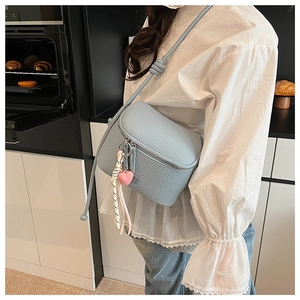 Dettaglio borsa a tracolla azzurra in pelle litchi con ciondolo a cuore e foulard