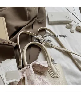 Detail of cream bucket bag with lychee pattern leather and adjustable shoulder strap