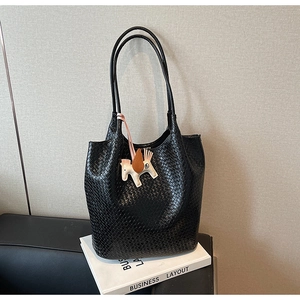 Close-up of black woven shoulder bag featuring a horse charm and intricate texture