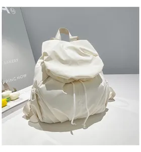 Detail of white puffer backpack featuring pleated drawstring texture and soft padded nylon fabric