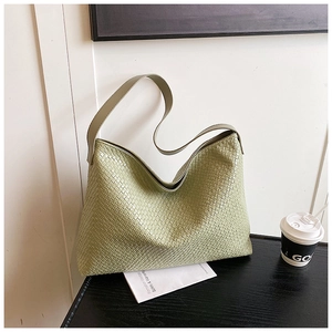 Detail of light green woven tote bag showing premium texture on a dark wooden table