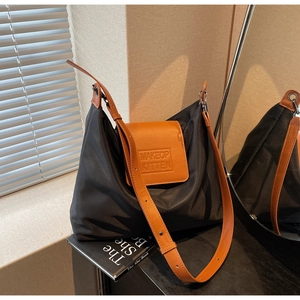 Détail du logo gaufré sur le sac cabas en nylon noir et cuir marron avec bandoulière