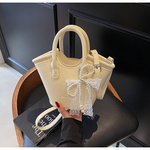 Detailed close-up of cream-white bucket bag featuring lychee grain PU and pearl lace bow