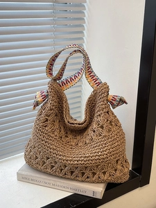 Large woven straw tote bag with floral openwork patterns and a colorful geometric ribbon