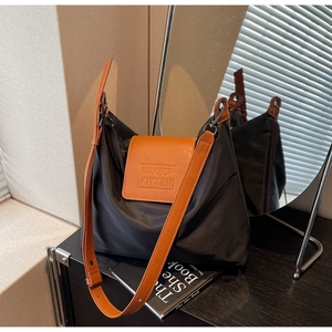Détail du sac en nylon noir avec rabat en cuir orange et logo embossé élégant