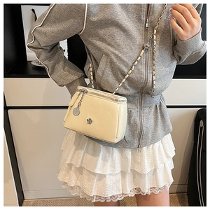 Détail du sac bandoulière en cuir crème avec bandoulière chaîne et fleur métallique