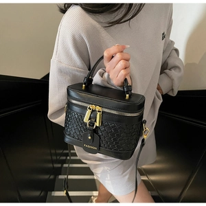 Detail of black woven PU vanity bag with gold zippers and detachable leather strap