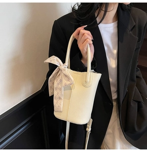 Detail of cream bucket bag with lychee texture and decorative silk scarf on model