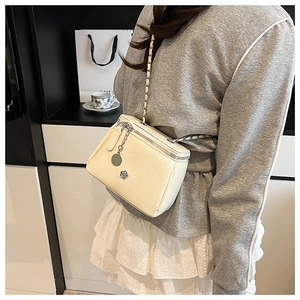 Vue détaillée du sac bandoulière crème avec breloque fleurie sur cuir souple