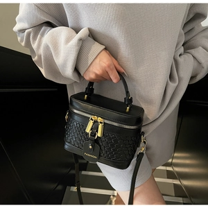 Close-up of black PU bucket bag with woven texture, gold zippers and fashion tag detail