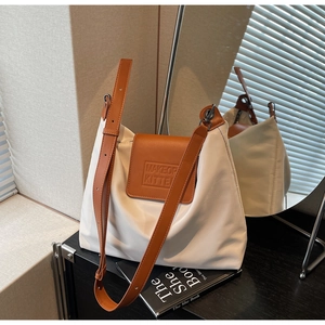 Détail du sac cabas crème avec bandoulière en cuir marron et logo embossé élégant