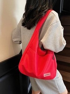 Vibrant red canvas hobo shoulder bag with a wide strap shown on a model for daily use