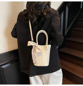 Litchi pattern bucket bag with decorative scarf shown on a model in a minimal setting
