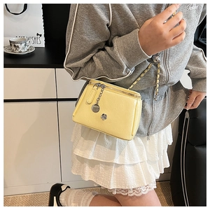 Sac bandoulière jaune en cuir PU avec chaîne et breloque fleurie porté par un mannequin