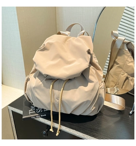 Detail of minimalist beige nylon backpack with drawstring closure and side storage pocket