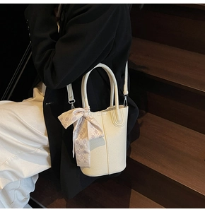 Detailed macro view of the cream leather bucket bag with an elegant silk scarf wrap