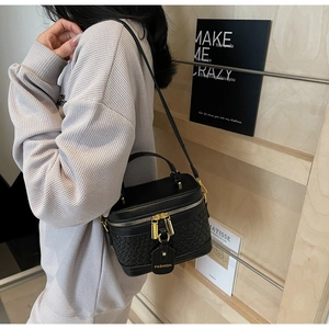 Detail of black quilted bucket bag featuring dual gold zippers and fashion leather tag