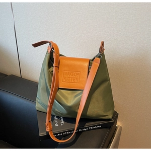 Détail du sac fourre-tout en nylon vert armée avec rabat en cuir brun et logo gaufré