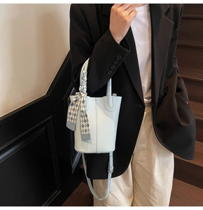 Detail of light blue lychee pattern bucket bag with silk scarf on a model