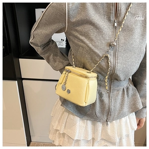 Détail du mini sac bandoulière jaune en cuir grainé avec bandoulière chaîne et pendentif fleur