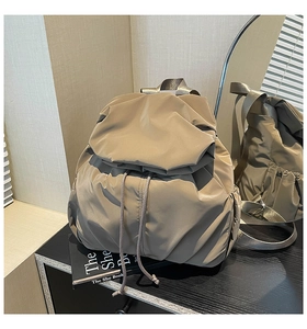 Detail of khaki nylon backpack featuring drawstring closure and textured褶皱 fabric surface