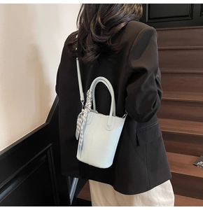 Detail of light blue bucket bag with pebble leather texture and checkered silk scarf