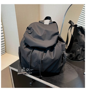 Detail view showing black nylon backpack with drawstring closure and side pockets