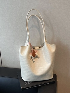 Chic beige woven texture tote bag with leather horse charm on a stylish black sofa
