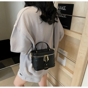 Fashionable black PU bucket bag with woven texture and gold zippers shown on a model