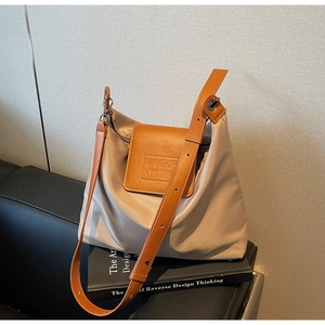 Détail du sac fourre-tout en nylon kaki avec rabat en cuir orange et bandoulière