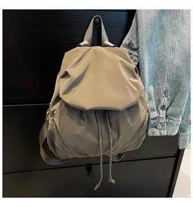 Detail of large beige backpack with flap closure and lightweight wrinkled texture fabric