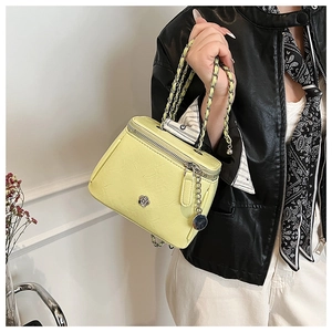 Détail d'un sac jaune avec ornement camélia en métal et bandoulière en chaîne dorée